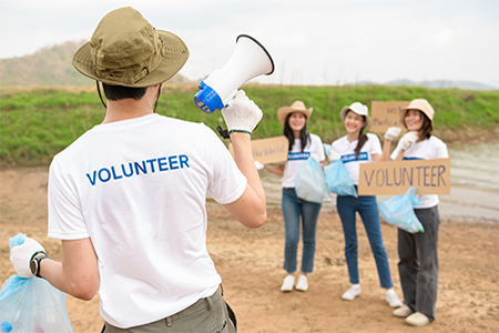 Volunteers from the youth community using rubbish bags cleaning up nature