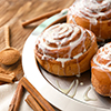 Plate with tasty cinnamon buns on wooden table, closeup