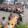 large group of people sitting at outdoor festival with food and wine