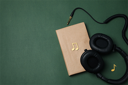Book and headphones on dark green background,