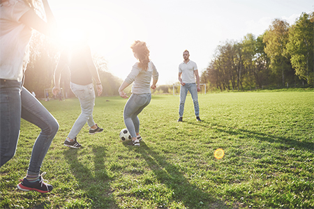 A group of friends in casual outfit play soccer in the open air
