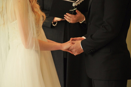 close up of bride and groom holding hands during wedding