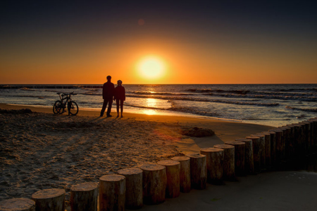 Family with bicycles on the Baltic Sea at sunset