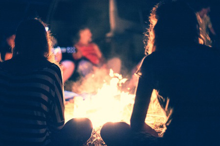 group of people sitting around bonfire