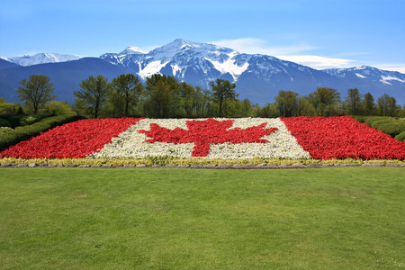 Canada flag done in red and white begonia flower against a backdrop of the Rocky mountains.