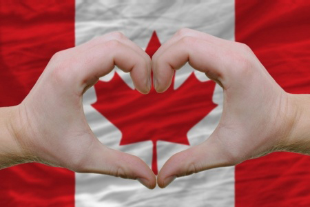 hands forming heart shape over canada flag