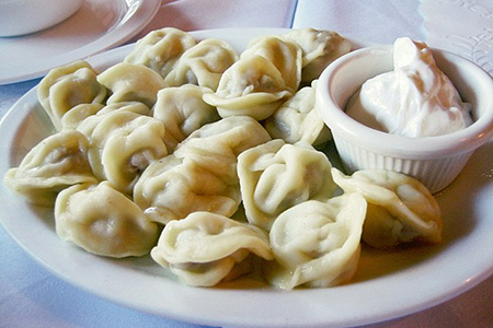 Russian Pelmeni on plate with white dipping sauce
