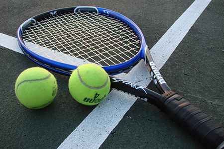 Shot of a tennis racket and two tennis balls on a court. 