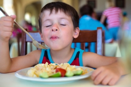 Child eating pasta with vegetables