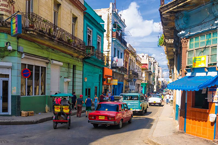 People and old cars in a central street in Havana