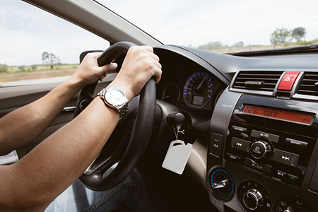 Stock Photo - male hands on steering wheel on the right with country side view