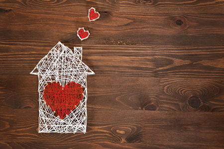Handmade home symbol with heart shape on wooden background with copy space