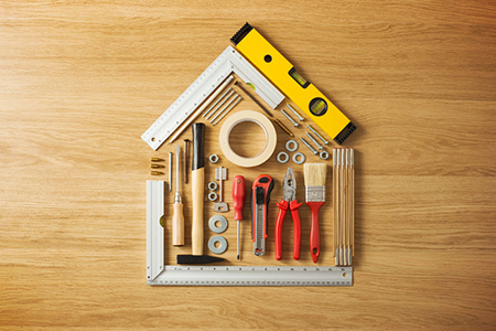 Conceptual house composed of DIY and construction tools on hardwood flooring, top view