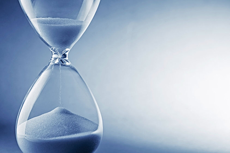 Closeup hourglass clock on light blue background