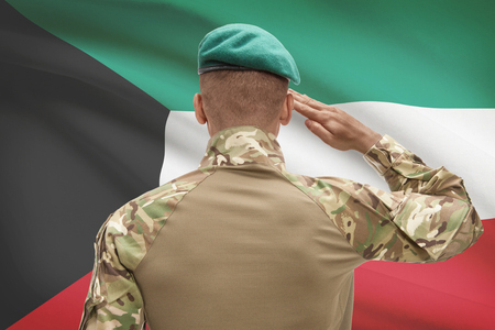 soldier in hat facing Kuwait flag