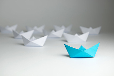 Leadership concept using blue paper ship among white