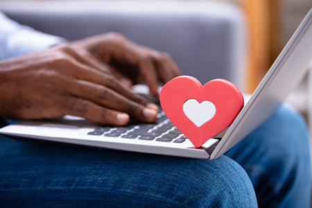 Close-up Of Red Heartshape On Keypad While Man's Hand Using Laptop