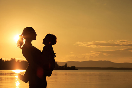 Mother and son playing on the coast of lake in the mountains of at the sunset time. Concept of frien