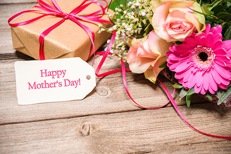 Bunch of flowers and tag with text on wooden background. Happy Mothers Day