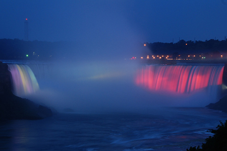 Niagara falls lit up with coloured lights at night time
