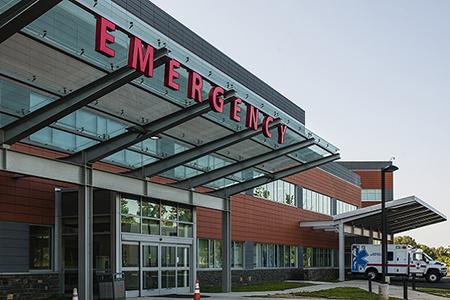 View of ER sign outside hospital - ambulance in background