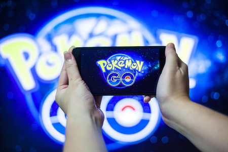 Hand holding a cellphone to play Pokemon Go with blur background