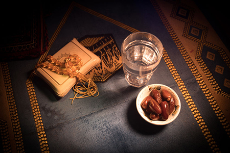 dates, water and holy book on prayer rug