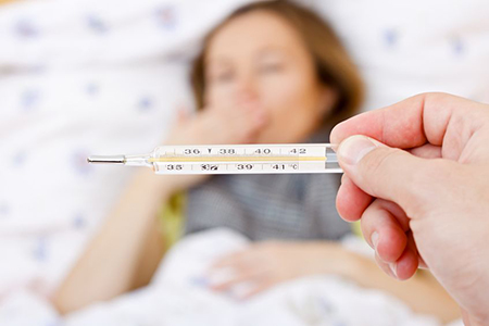 Young sick woman laying on bed having high fever