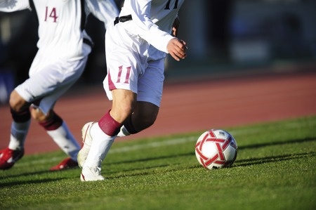 2 soccer players on field playing. cropped legs