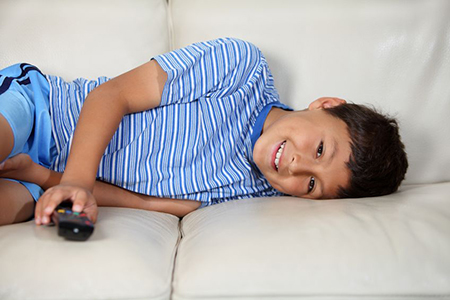 Young boy watching TV with remote control