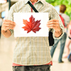 man at airport with sign with maple leaf