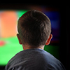 A young boy is watching a television screen