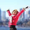 woman in canada parka raising arms and smiling