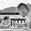 father and daughter doing homework on table outdoors