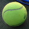 Shot of a tennis racket and two tennis balls on a court. 