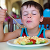 Child eating pasta with vegetables