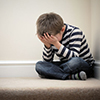 Upset problem child with head in hands sitting on staircase concept for bullying, depression stress 