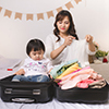 Asian mom and baby girl with suitcase baggage and clothes ready for traveling on vacation