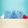 DAD text letters with white and red hearts over blue wooden background