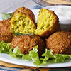 falafel on a white plate with lettuce and sauce