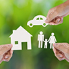 Hand holding a paper home, car, family on green background