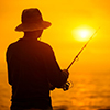 Fisherman silhouette at sunset near the sea with a fishing rod