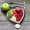 heart shaped bowl filled with healthy snacks, such as fruit. Wrapped in stethoscope 