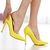 Woman taking off yellow high heels shoes.