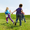 group of happy kids playing tag game and running on green field outdoors