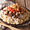 Arabic cuisine: kushari of rice, pasta, chickpeas and lentils close up on a plate on the table. hori