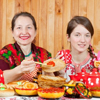 Girl in traditional clothes eating pancake during Maslenitsa festival
