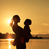 Mother and son playing on the coast of lake in the mountains of at the sunset time. Concept of frien