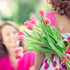 Woman and child with bouquet of flowers against green blurred background. Spring family holiday conc