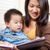 Mother reading book to child on lap